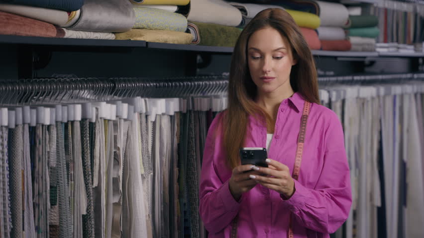 Caucasian woman happy amazed excited girl female fashion designer saleswoman cloth tailor using mobile phone shock wonder surprise receive amazing news on smartphone smile laugh in fabric textile shop