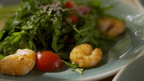 Woman eating a salad with herbs, tomatoes and shrimp. Keto diet concept. Vertical video.