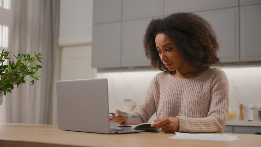 African American girl student ethnic woman studying with laptop at home working distant quarantine education female freelancer businesswoman writing notes in notebook on kitchen table computer work Royalty-Free Stock Footage #3486855195