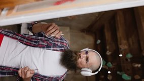Guy with headphones listening to music. Moving paint brush artist works on abstract oil painting in creative modern studio. vertical video.