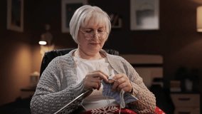 Knitting. Senior woman who looks like grandmother sits in chair and knits handmade item - Powered by Shutterstock - Get 15% off with code: PIKWIZARD15
