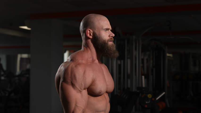 Caucasian bald topless man doing an exercise with a barbell in the gym. Bicep curls with weights. Royalty-Free Stock Footage #3486992915