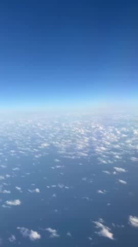 Take pictures of the beautiful cloud scenery and blue sky outside the window on the plane