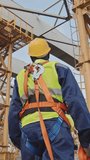 Vertical low angle shot of unrecognizable African-American worker in hardhat and safety belt walking along construction site - Powered by Shutterstock - Get 15% off with code: PIKWIZARD15