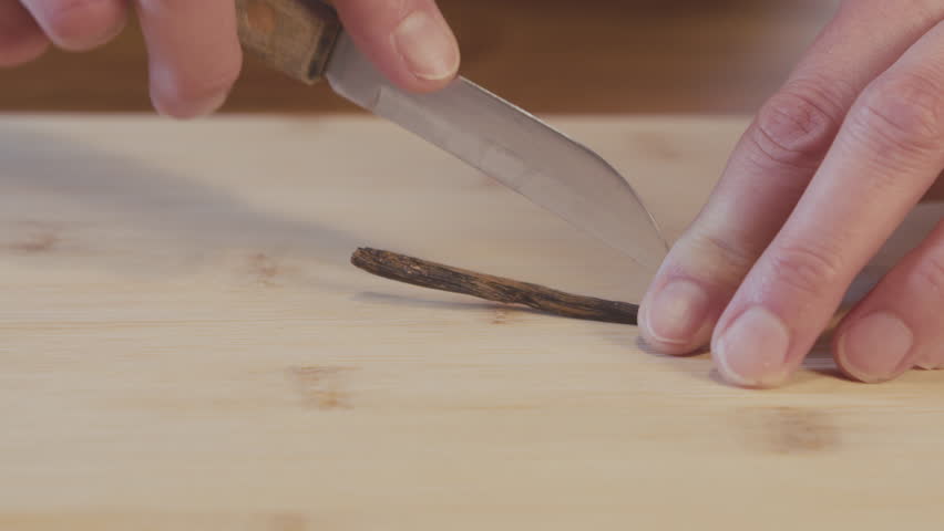 Close up of a woman chef peeling, cutting and removing the inside of vanilla stick. Kitchen, interior, studio shot. High quality 4k footage