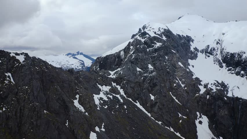Snowy mountain peaks in Fiordland, New Zealand, South Island. Aerial descent.