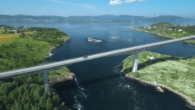 A drone hovers high and rotates to reveal a panoramic view of the Saltstraumen Bridge across the Saltfjorden fjord and the renowned Saltstraumen tidal current with powerful swirls with lush landscapes