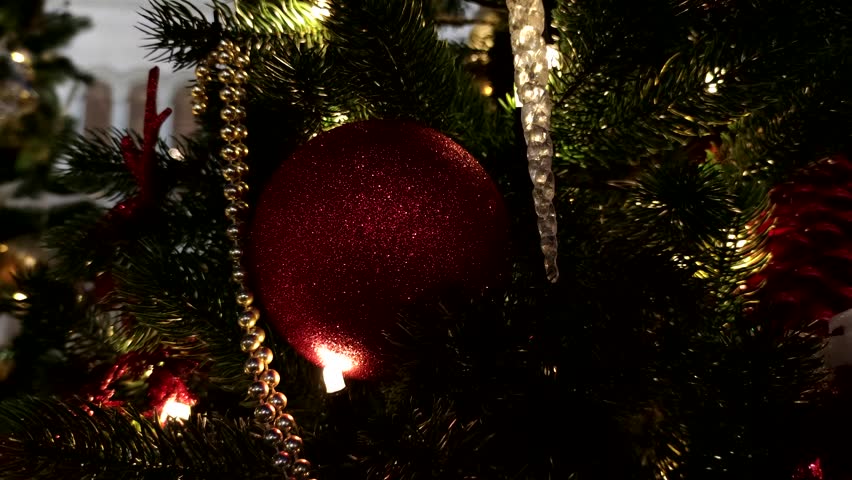 Close-up view of colourful Christmas baubles and light garland hanging on Christmas trees next to Cathedral of Christ the Saviour in a dark winter night in Moscow, Russia. Slow motion handheld video.