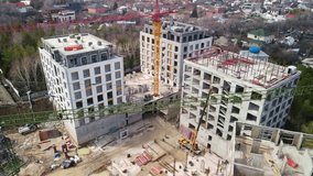 Aerial video footage from a drone of the construction of a multi-storey building, workers carry out work on the construction of the next floor of the building. Construction of load-bearing walls.