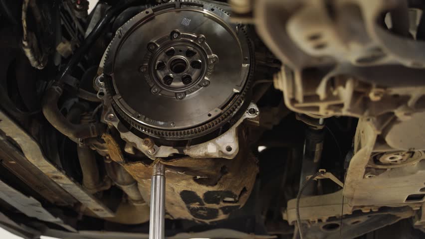 Mechanic installs new clutch disc in car. Automotive repair workshop scene, hands replace worn components. Vehicle maintenance, clutch assembly, gearbox service. DIY auto workshop instruction.