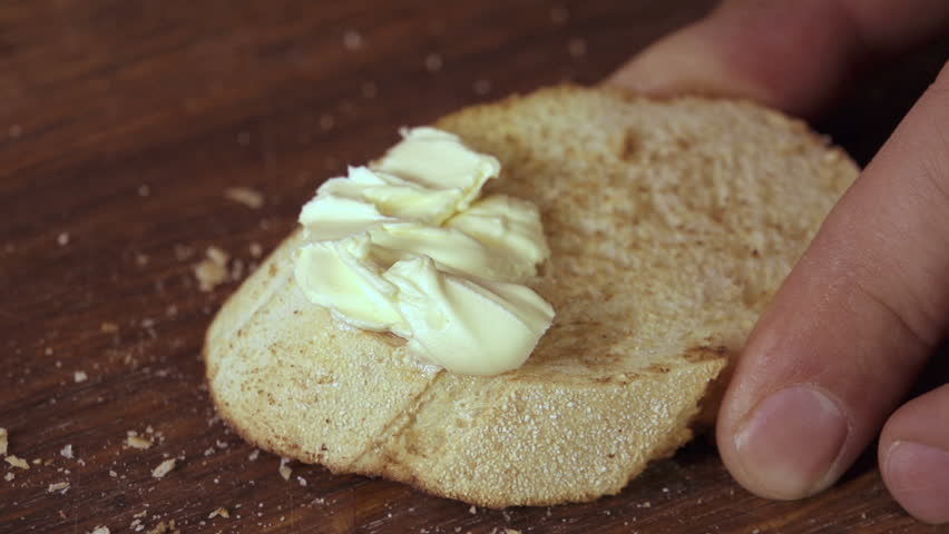 hand spreading butter on bread