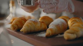 Recipe. A pastry chef wearing an apron effectively sprinkles powdered sugar on fresh baked goods. Experienced worker sprinkles with powdered sugar, masters new techniques for baking croissants - Powered by Shutterstock - Get 15% off with code: PIKWIZARD15