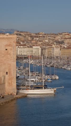 Yachts coming to Marseille Old Port (Vieux-Port de Marseille) on sunset and Fort Saint-Jean. Marseille, France. Camera pan