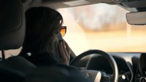 a young woman driving a car,speak on the phone, seen from the backseat. Reflecting on solitude, contemplation, or daily routines, this video resonates with viewers on a personal level. Suitable for li