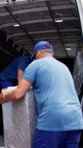 Male Workers In Blue Uniform Unloading Furniture From Truck