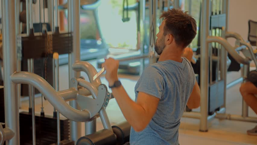 Man Weight Lifted Exercising In Gym Cable Pushdown. Multi-gym Workout. Chest Workout Push Down Biceps Curls. Indoor Bodybuilding Lifting Weight. Fitness Exercising In Sport Gym. Cable Triceps Pushdown Royalty-Free Stock Footage #3487380553