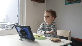 Young Boy Intently Watching Educational Content on Tablet During Breakfast