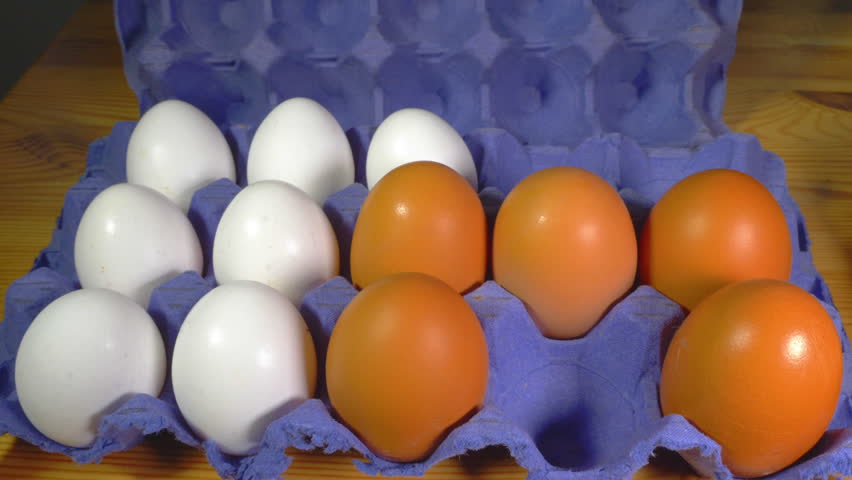 Closeup of a man’s hand adding larger brown chicken or hen’s eggs to the white ones in a cardboard box, with the last one being an extra large egg. Royalty-Free Stock Footage #3487483483