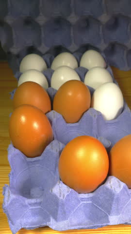 Vertical video - Closeup of a man’s hand adding larger brown chicken or hen’s eggs to the white ones in a cardboard box, with the last one being an extra large egg. Royalty-Free Stock Footage #3487483529