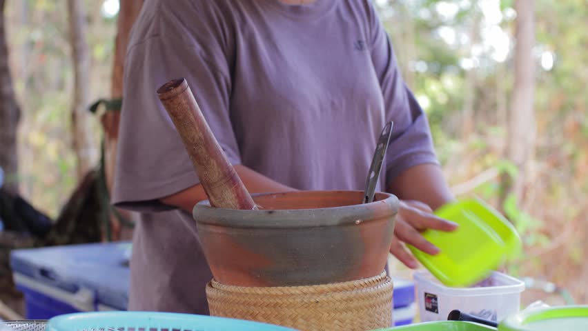 The vendor is making papaya salad. Looks delicious