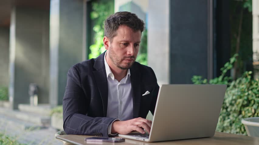 Handsome 30s top manager work laptop. Entrepreneur type computer macbook. Business man look monitor. Young male businessman. Urban city background. 40s employee create start up. Ceo office boss job.