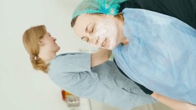 Vertical video in which a beautician applies a mask to the face. The client wants her skin to look healthy and young. High quality 4k footage