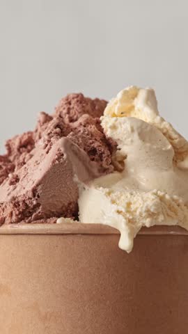 Close up of roating vanilla and chocolate flavor ice cream in brown paper take away cup. Summer dessert