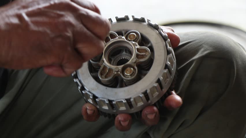 Motorcycle mechanic assembling parts of motorcycle engine components.