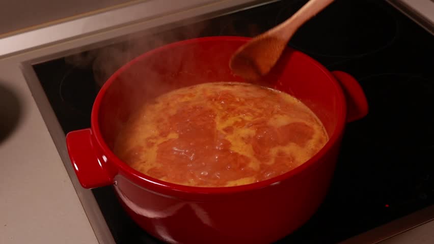 woman cooking delicious vegetable soup in a red pot on the stove at home, capturing the warmth and comfort of homemade cuisine
