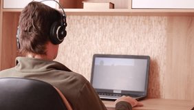 Sitting with headphones in front of computer