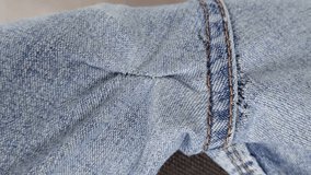 Hand-sewn holes on jeans, seams from sewing on the outside of denim