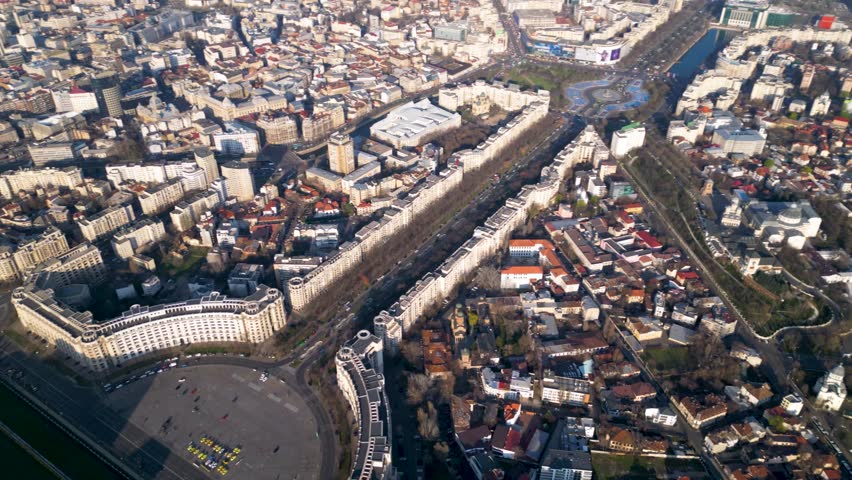 High angle drone footage of the Palace of the parliament in Bucharest Romania. Constitution Square seen from above on a sunny green day. Ceausescu