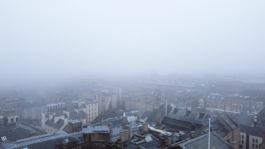 Aerial view backwards passing the St Giles cathedral, in foggy Edinburgh, Scotland