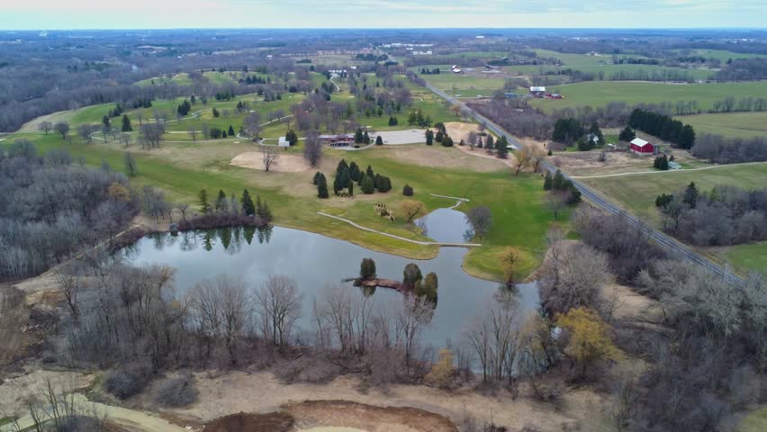 aerial flyover of a golf course in the countryside with a lake during spring (Wisconsin)