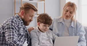 Happy child boy with family watching laptop, winnig computer game, father, mother close together to enjoy. Sitting at home, having good time together, celebrating distant learning high result, amuse 