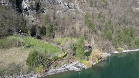Drone clip showing remote wooden lakeside hut in Swiss Alps, surrounded by trees
