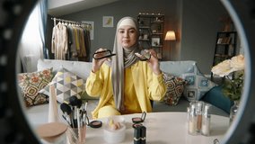 Beauty blogger woman making video. Muslim woman in hijab shows eye shadow, talks, speaking about brands, makeup, pros and cons of eye shadow palettes. Beauty blogger woman making recording video.