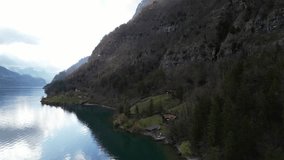 Panning drone clip showing remote lakeside wooden hut, perfect for a hiking vacation, in Swiss alpine mountains