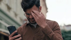 Close up upset unhappy Indian Arabian ethnic man young guy businessman male using looking mobile phone bad connection losing fortune loss fail touch head why negative result outdoors city urban street - Powered by Shutterstock - Get 15% off with code: PIKWIZARD15