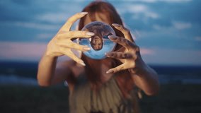 Contact juggling with an acrylic ball is performed by a beautiful red-haired girl against the backdrop of an evening blue sky. She lifts the ball in front of her, and her inverted reflection appears - Powered by Shutterstock - Get 15% off with code: PIKWIZARD15