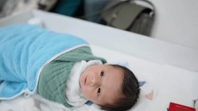 Slow-motion video of an 8-day-old Taiwanese baby sleeping on the sofa wrapped in a blue wrap