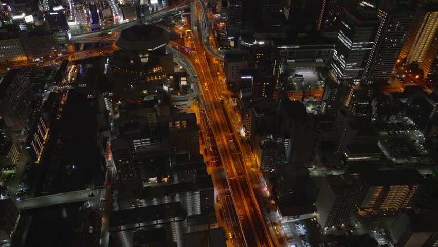 High angle view of buildings and streets in city. Tilt up revealing night cityscape. High rise office or residential towers in metropolis. Osaka, Japan