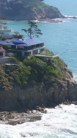Vertical video. Drone shot of luxury houses located on the rocky coast of Pacific Ocean, Laguna beach, Orange County, California, West coast, USA. cenic view of rocky shoreline with private residences