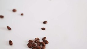Coffee beans falling pouring close up on white surface background. Heap of fried coffee beans. Aromatic, invigorating, addictive drink.