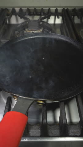 Vertical video - Closeup of a man’s hands using a knife to crack a large double yolk hen’s egg into a steaming hot frying pan, on a kitchen stove. Royalty-Free Stock Footage #3488352447