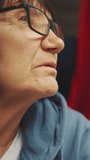 Vertical video, Close up portrait of pensive old woman with glasses resting in a chair and looking out the window of a train while traveling, Slow motion