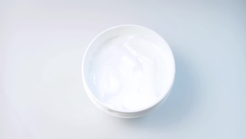 Skin care cream commercial. Woman finger touching skin care cream in a white round jar. A close-up shot