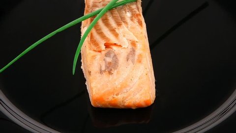 healthy fish cuisine : baked pink salmon steaks with green onion on black dish isolated over white background