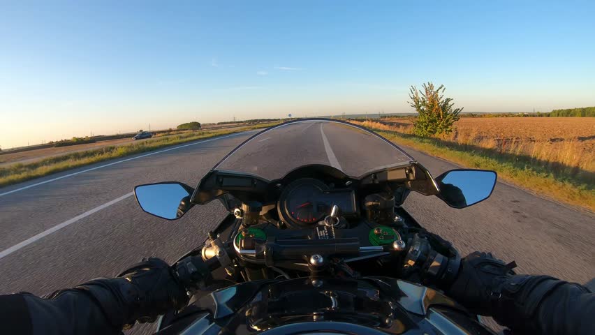 The viewpoint of motorcyclist driving motorbike at speed highway. Point of view of motorcycle rider rides fast in country road. Guy racing his motor bike during summer journey. Road trip concept. POV