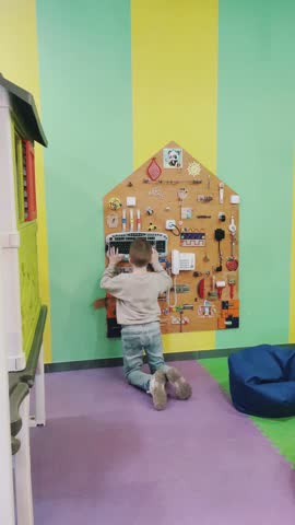 a busy boy plays on a special wooden board with various elements for the active development of fine motor skills and thinking in a bright children